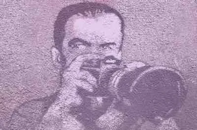 Stencil street art of a photographer raising a camera to his eye