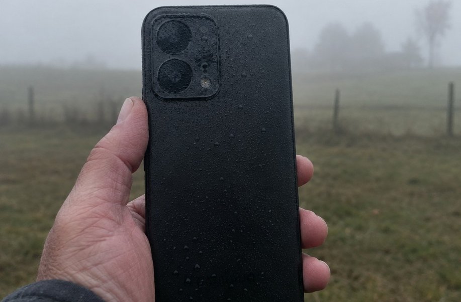 Fine condensation droplets across a phone camera lens held up in cold damp air